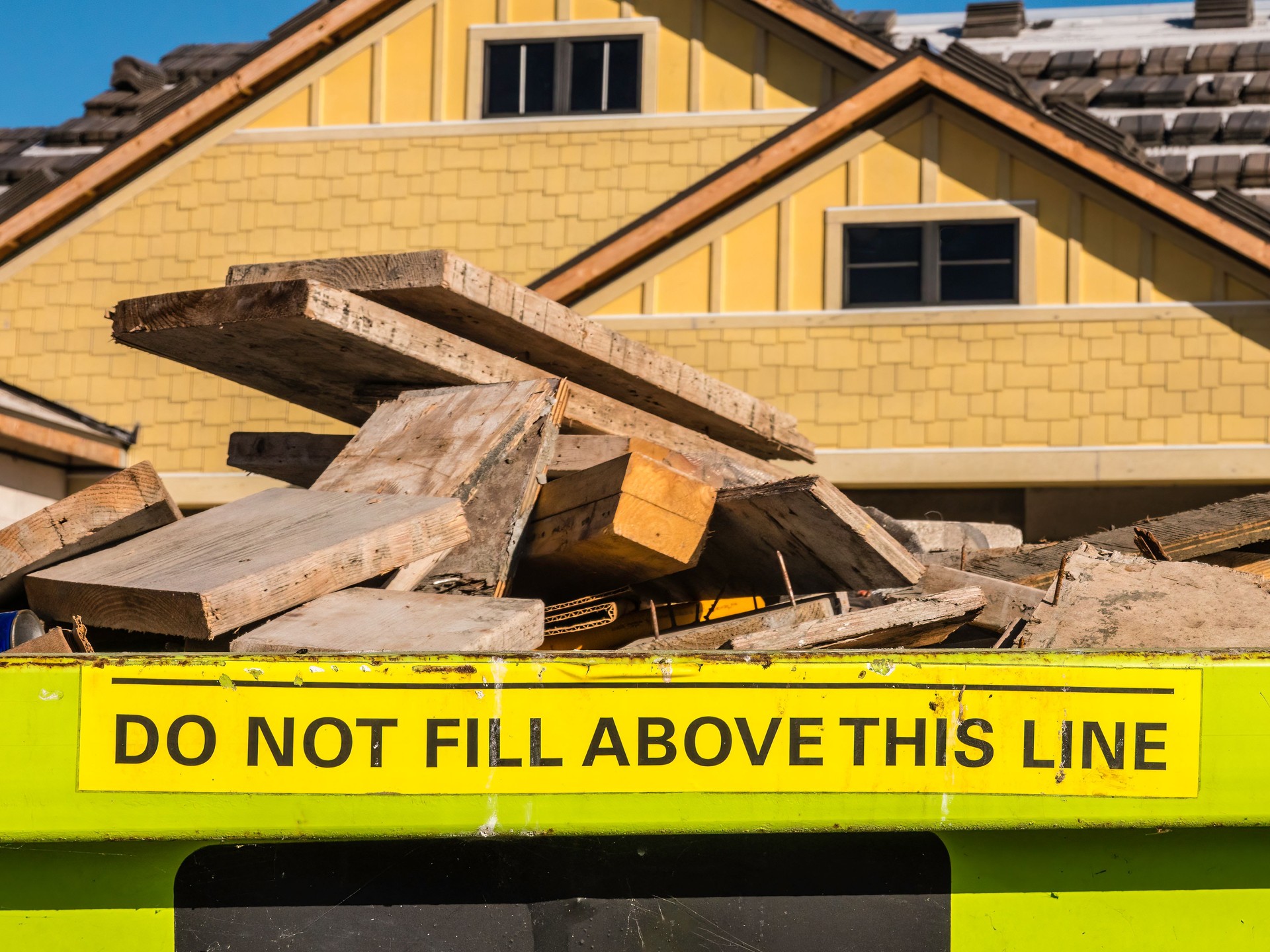 Sign at top of overfilled industrial garbage bin on construction site